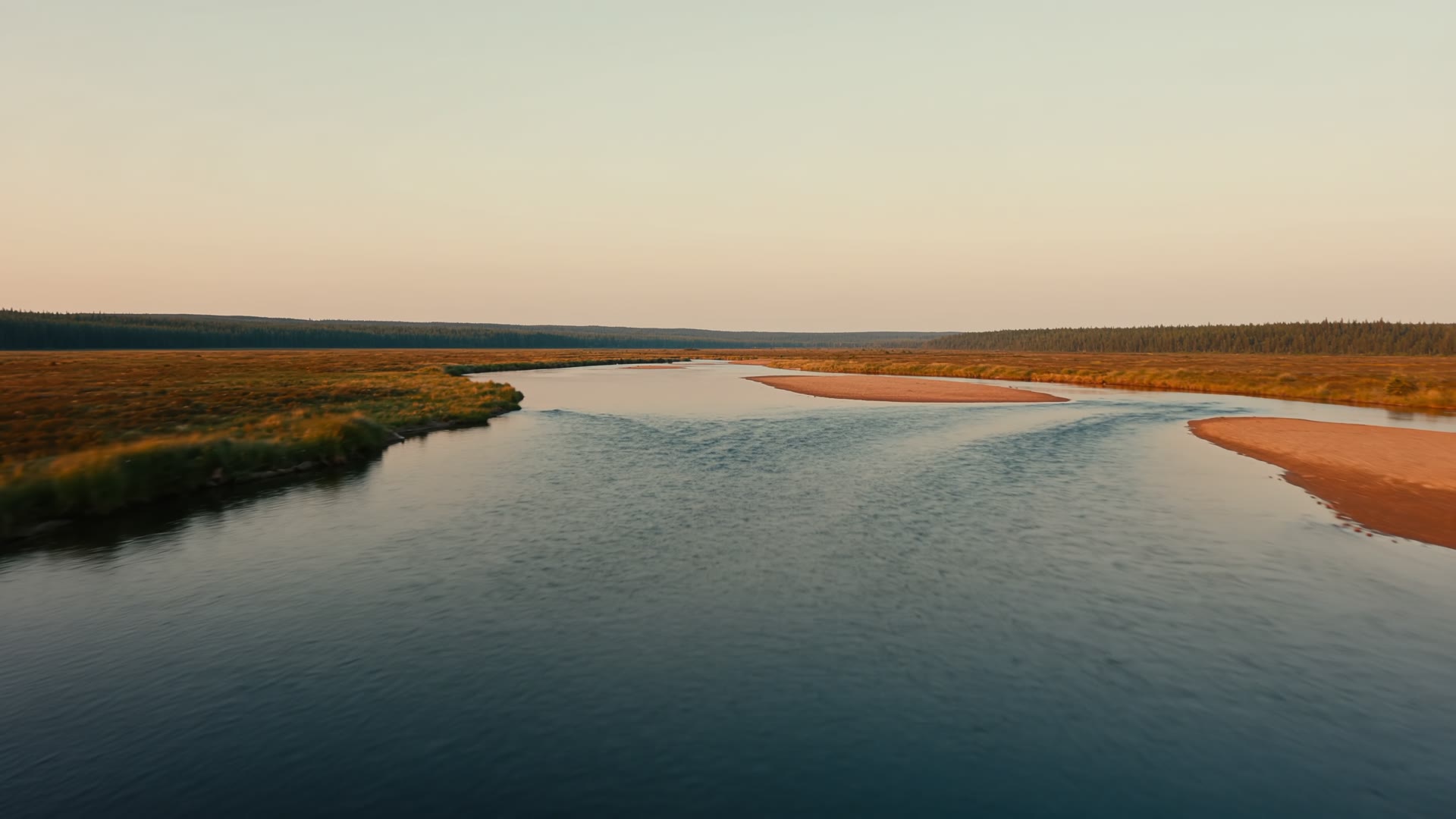 Aerial view of a river winding through a valley at golden hour